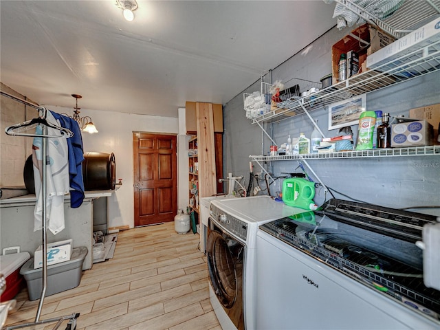 clothes washing area with washer and clothes dryer and light hardwood / wood-style floors