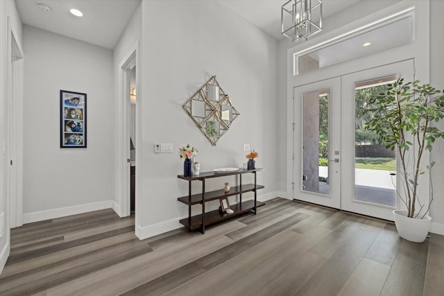 entryway featuring dark wood-type flooring, an inviting chandelier, and french doors