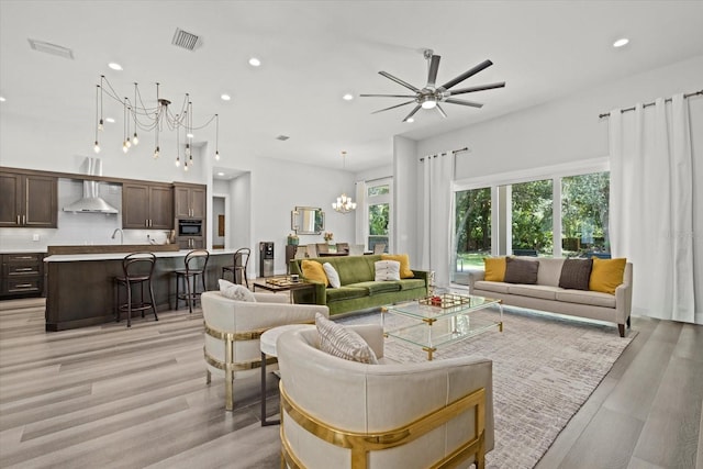 living room featuring ceiling fan with notable chandelier and light hardwood / wood-style floors