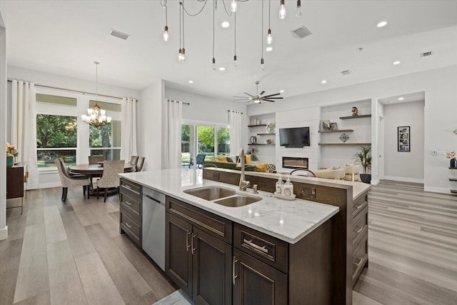 kitchen with ceiling fan with notable chandelier, dishwasher, pendant lighting, sink, and light stone counters