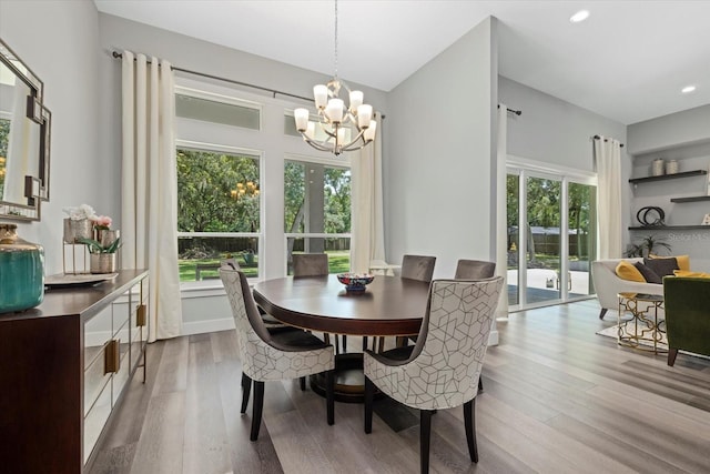 dining space with light wood-type flooring, plenty of natural light, and a notable chandelier