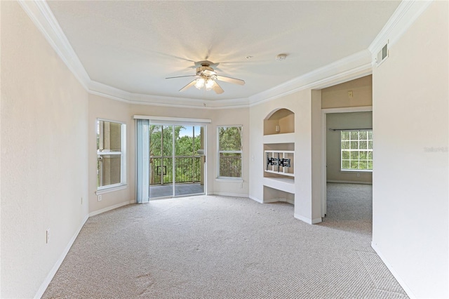 empty room featuring light carpet, ornamental molding, visible vents, and built in features