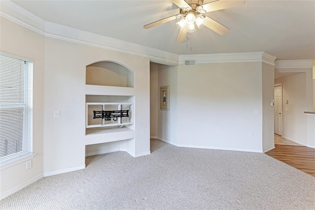 carpeted empty room featuring built in features, crown molding, and ceiling fan