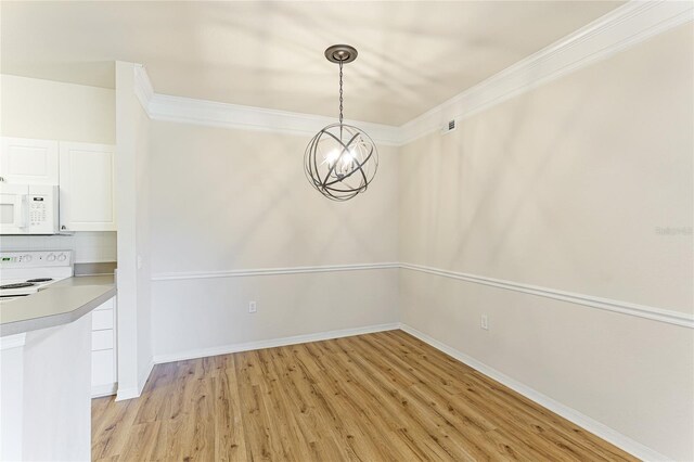 unfurnished dining area featuring light hardwood / wood-style flooring, crown molding, and an inviting chandelier