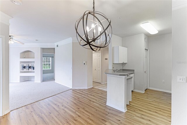 kitchen featuring ceiling fan with notable chandelier, pendant lighting, light carpet, white cabinetry, and kitchen peninsula