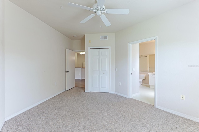 unfurnished bedroom with ceiling fan, a closet, light colored carpet, and ensuite bathroom