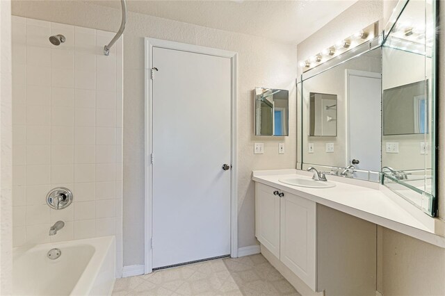 bathroom featuring tiled shower / bath combo, vanity, and tile patterned flooring