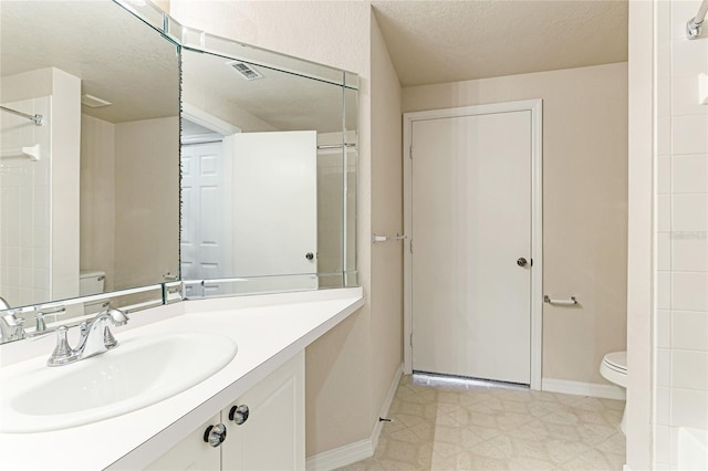 bathroom featuring vanity, a textured ceiling, toilet, and tile patterned flooring