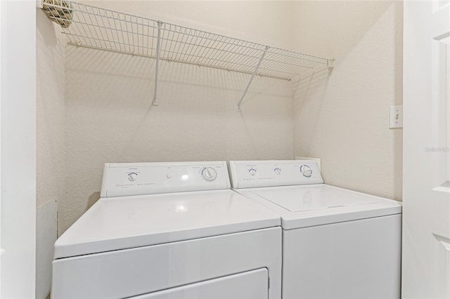 washroom featuring laundry area, separate washer and dryer, and a textured wall