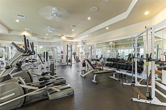 exercise room with ceiling fan and a tray ceiling