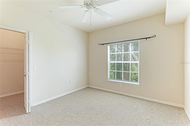 empty room with light colored carpet, ceiling fan, and baseboards