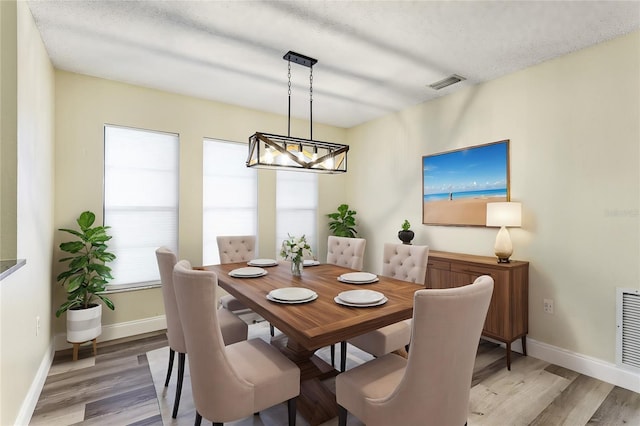 dining area with a textured ceiling and light hardwood / wood-style flooring