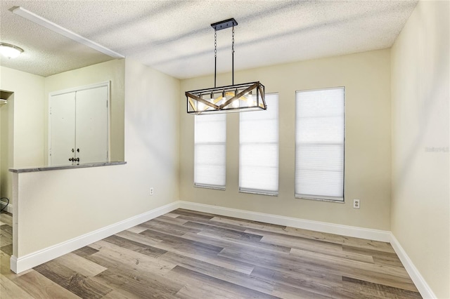 unfurnished dining area featuring baseboards, a healthy amount of sunlight, and wood finished floors