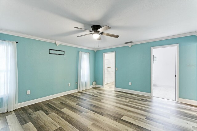 empty room with ceiling fan, hardwood / wood-style flooring, crown molding, and a healthy amount of sunlight