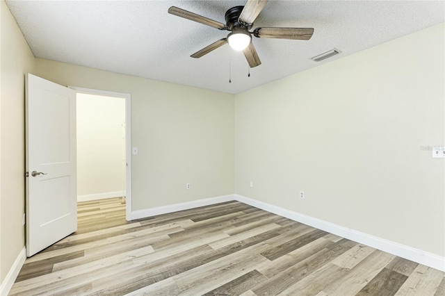 spare room featuring visible vents, light wood-style flooring, a textured ceiling, and baseboards