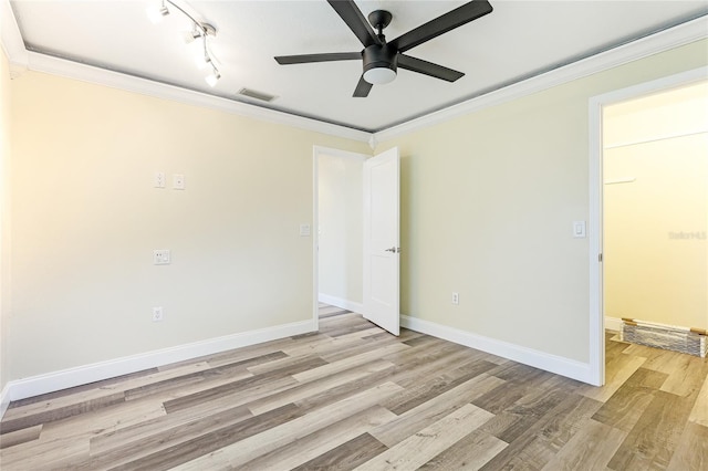 spare room featuring baseboards, visible vents, ceiling fan, crown molding, and light wood-type flooring