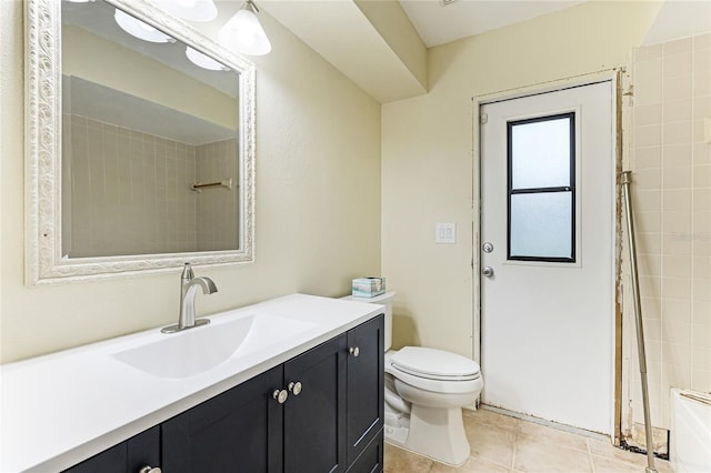 bathroom featuring tile patterned flooring, toilet, a tile shower, and vanity