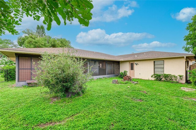 rear view of property featuring a sunroom and a lawn