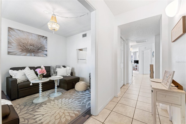 living room with a chandelier, a textured ceiling, and light tile patterned floors