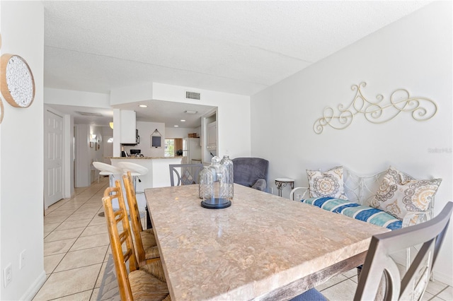 dining space with a textured ceiling and light tile patterned floors