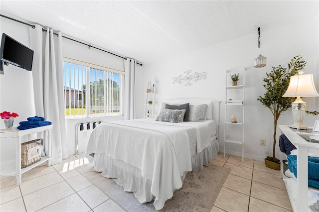 bedroom featuring light tile patterned flooring, radiator, and a textured ceiling