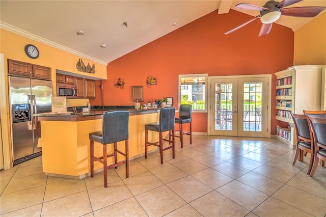 kitchen with beamed ceiling, stainless steel appliances, a breakfast bar, french doors, and ceiling fan