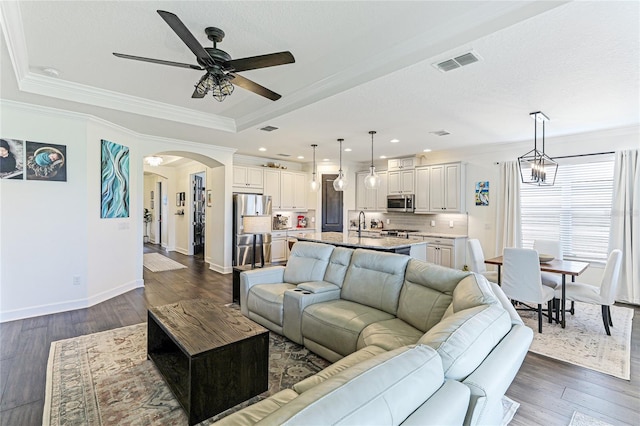 living room with ceiling fan, crown molding, dark hardwood / wood-style flooring, and a tray ceiling