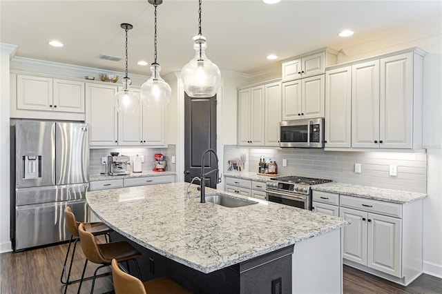 kitchen featuring stainless steel appliances, an island with sink, sink, and decorative light fixtures