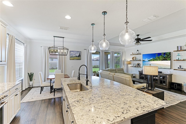 kitchen with sink, light stone counters, crown molding, a center island with sink, and dark hardwood / wood-style floors