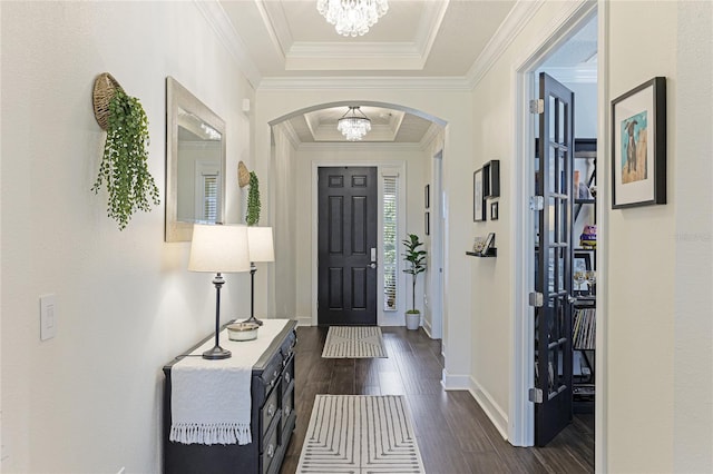 entrance foyer featuring a tray ceiling, crown molding, dark wood-type flooring, and a chandelier