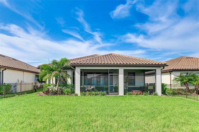 back of house featuring a lawn and a sunroom