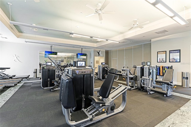 exercise room with a raised ceiling and ceiling fan