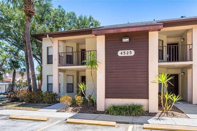 view of front of property featuring uncovered parking and a balcony