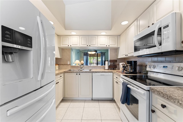 kitchen featuring light tile patterned flooring, white cabinetry, decorative backsplash, white appliances, and sink