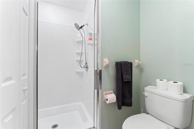 bathroom with a shower with shower door and toilet