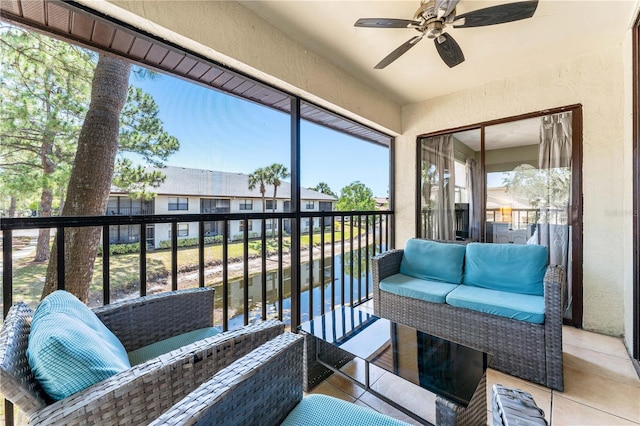 sunroom with ceiling fan and a water view