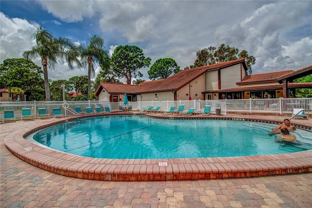 community pool with fence and a patio