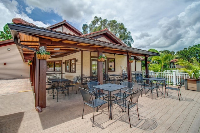 exterior space featuring outdoor dining area, a wooden deck, and fence