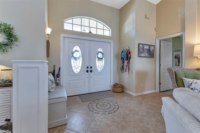 foyer with a high ceiling, light tile patterned flooring, and french doors