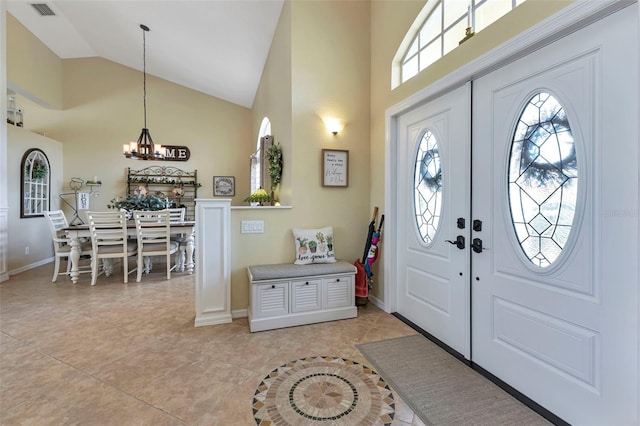 foyer entrance featuring high vaulted ceiling, an inviting chandelier, and light tile patterned flooring