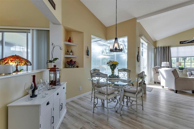 dining room featuring light hardwood / wood-style floors, vaulted ceiling, and built in features