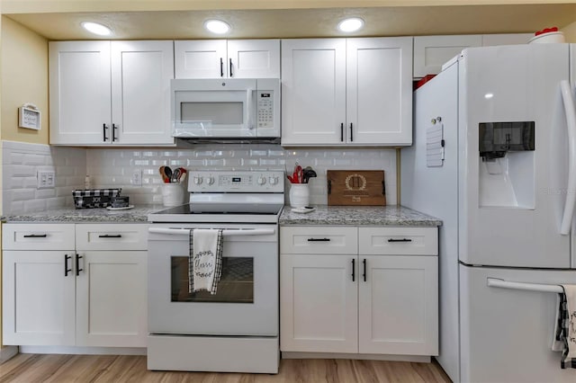 kitchen featuring backsplash, white cabinetry, light wood-type flooring, light stone countertops, and white appliances