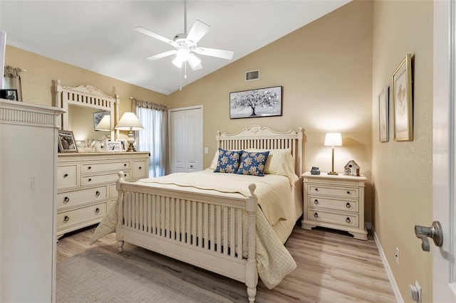 bedroom with ceiling fan, light wood-type flooring, vaulted ceiling, and a closet