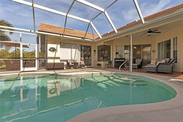 view of swimming pool featuring glass enclosure, ceiling fan, outdoor lounge area, and a patio area