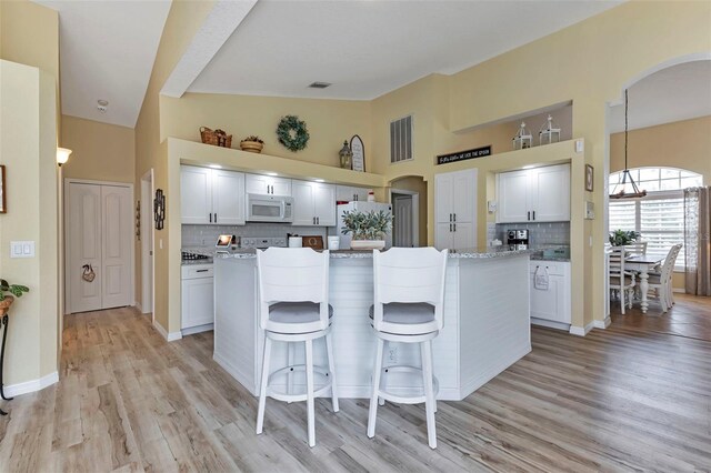 13791 Palmetto Point Ct, Port Charlotte, FL 33953 - kitchen with white appliances, arched walkways, a kitchen island, and tasteful backsplash