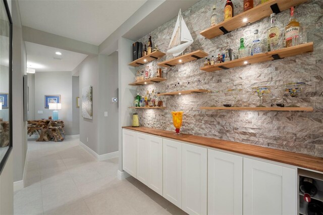 interior space with wood counters, light tile patterned flooring, and white cabinets