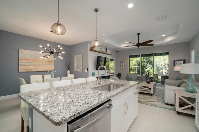 kitchen featuring white cabinetry, dishwasher, ceiling fan with notable chandelier, a raised ceiling, and sink