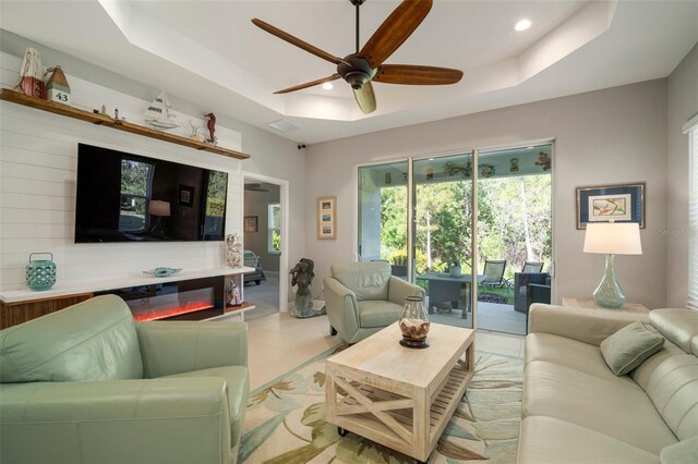 tiled living room featuring ceiling fan and a raised ceiling