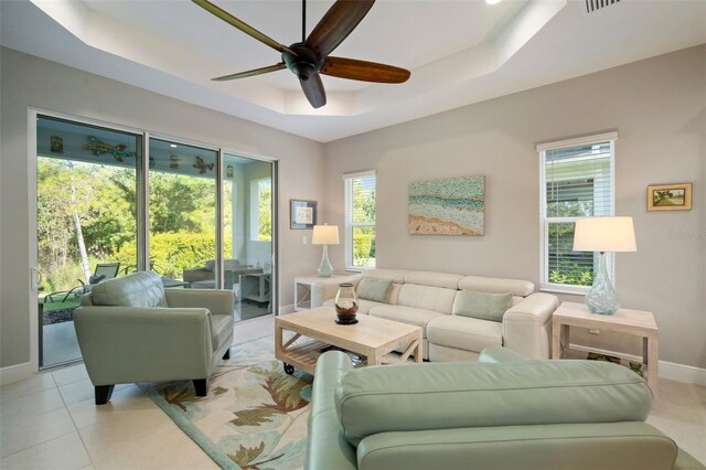 tiled living room with plenty of natural light, ceiling fan, and a tray ceiling