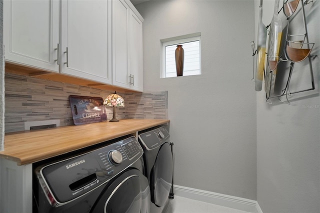 clothes washing area featuring separate washer and dryer and cabinets